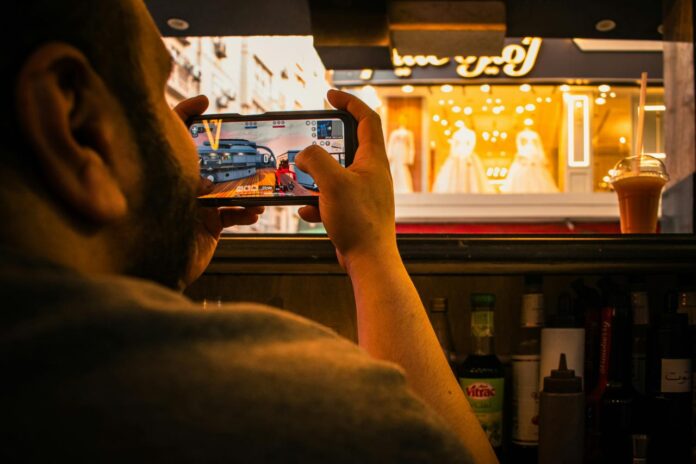 Man films a storefront window display with smartphone.