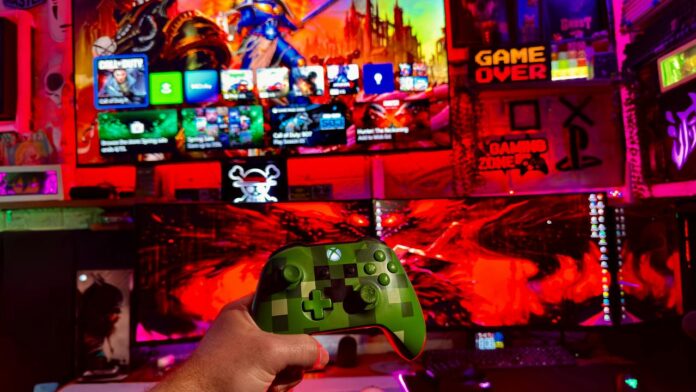 Person holding a video game controller in front of screens.